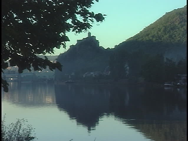 A building sits on a cliff across a hazy bay.