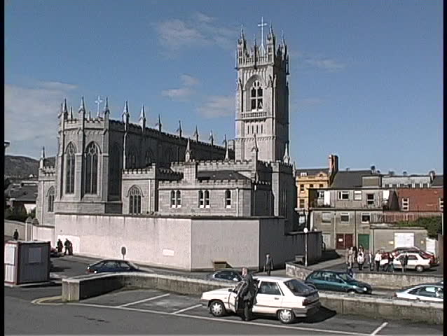 A medieval cathedral is surrounded by traffic in Ireland.