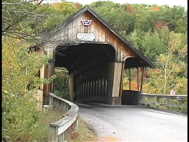Trees surround an old covered bridge in a peaceful forest in Maine.