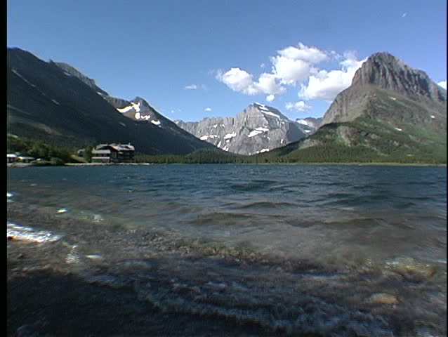 Waves ripple through a glacial lake with strong mountain peaks in the background at Glacier National Park in Montana.