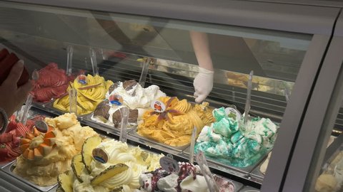 a sales assistant scoops out frozen gelato from a display cabinet in rome, italy