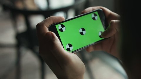 Close-up of male hands touching green screen on mobile phone. Guy zoom in and zoom out picture.  Green screen Chroma Key. Close up. Tracking motion. Horizontal   pants - Swipe left   right animation  Video de stock