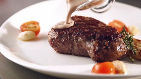 Grill smocked barbecue steak with a flowing sauce in slow motion