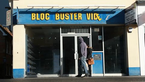Pedestrians pass bankrupt Blockbuster video store wide. Newbury UK. Feb 2014