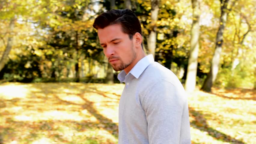 A young man walks in the woods, is a serious and looks around.