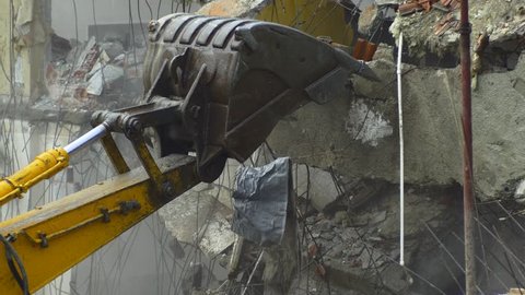 4K Building deconstruction with the heavy machinery. Tearing down old building on a construction site. Bulldozers turn old homes into rubble and dust fills the air. Digger using its bucket to demolish
