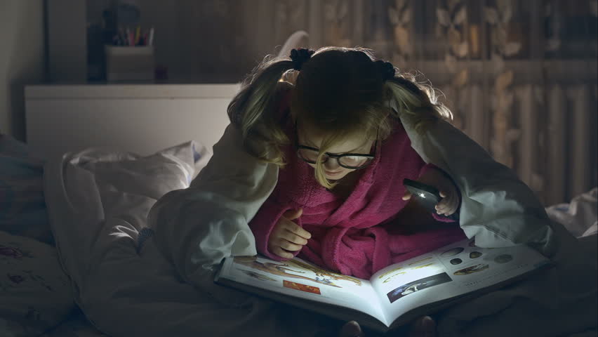 A young girl reading a book under the covers with a flashlight. RAW video record. | Shutterstock HD Video #14403370