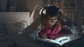 little girl sitting on the bed and reading a book - dolly motion. RAW video record.