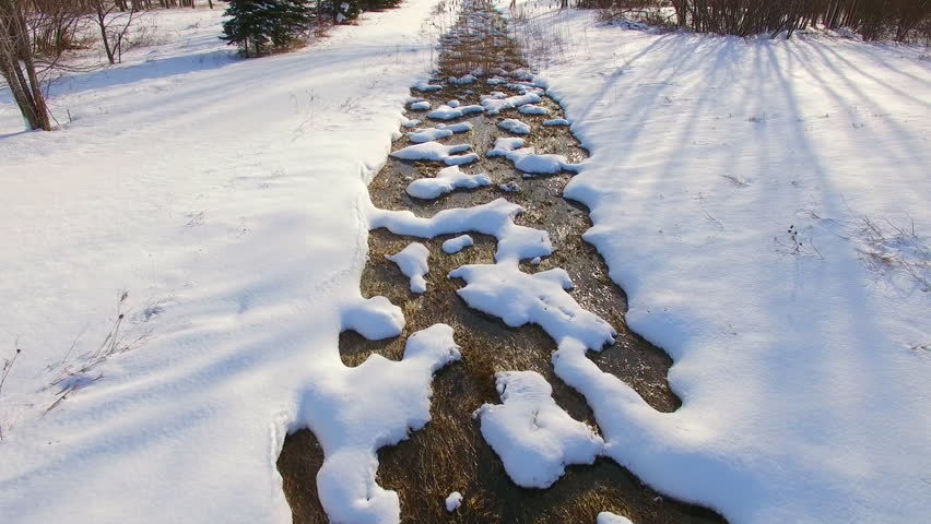 Flying low over tranquil stream blanketed in winter snow, somewhere in rural Wisconsin.
