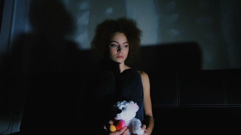 A girl holding a teddy bear and think of something sad. A young girl is upset and feels empty.