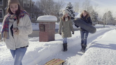 Happy Teens Carry Sleds And Walk Through Snowy Neighborhood