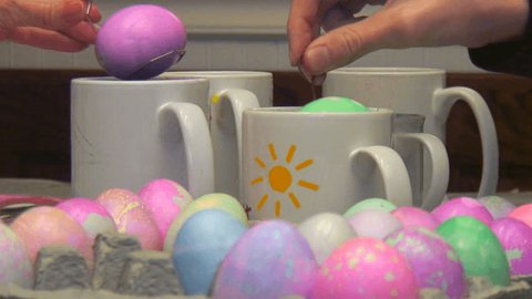 Close shot compilation of hands dipping Easter eggs into colorful dye   Stock Video