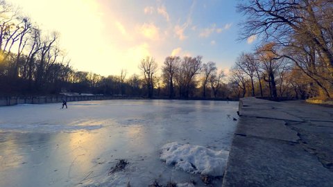 Frozen winter lake in a city park with trainees hockey player, time lapse