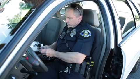 Anaheim, CA., January 2016: Police Officer checking his cell phone in a patrol car in Anaheim, CA., January 2016.