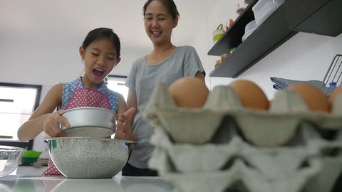 Happy Asian mother baking cookie with little daughter in apron, Pan shot