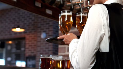 Smiling barmaid serving glasses of beer in bar