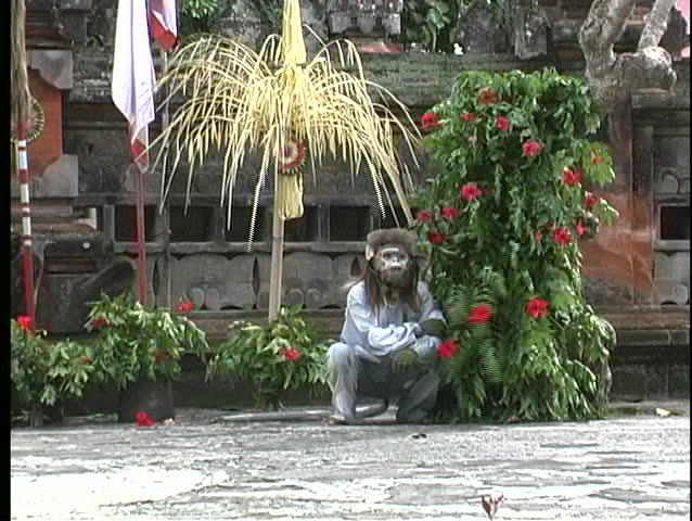 A Balinese dancer smiles and laughs at passersby on a street in Indonesia.