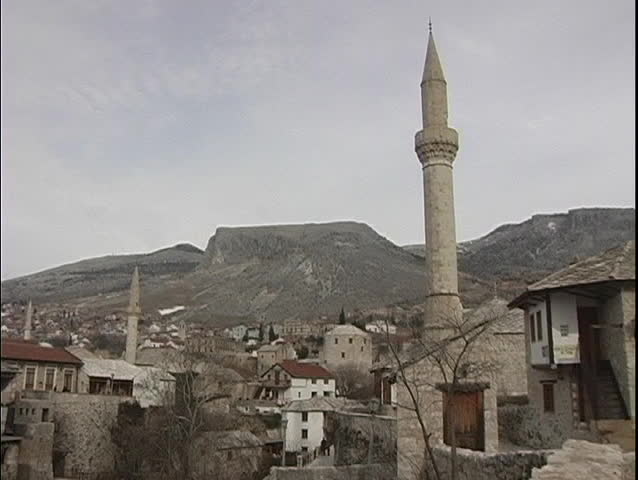 A medium shot of a church steeple, with roof-tops and houses in the background, in Yugoslavia.