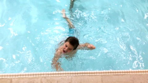 Young boy playing and splashing in swimming pool 4k