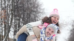 Couple enjoying their winter weekend together, guy holding his girlfriend piggyback