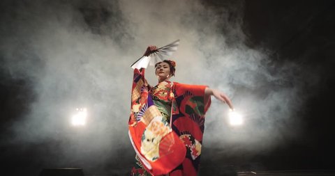 4K beautiful Japanese geisha dancing on stage and posing for the camera,the smoke in the background, slow motion
