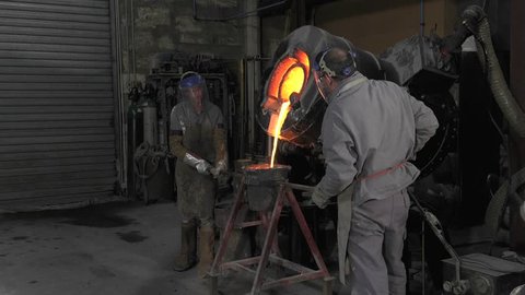 Lost wax bronze casting in a foundry/pouring the molten metal in the casting crucible