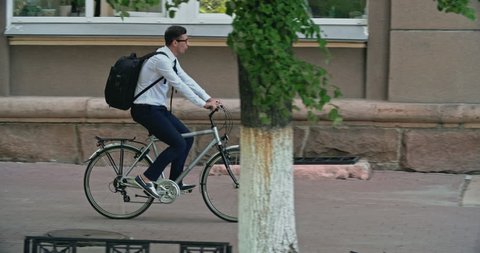 Mid adult office worker with backpack riding his bike to work, tracking shot Stock video