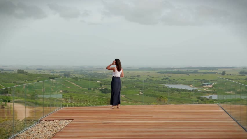 Young woman at the top of a hill overlooking at a beautiful view of a landscape