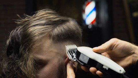 Barber cuts the hair of the client with clipper slow motion close up