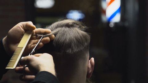 Barber cuts the hair of the client with scissors slow motion close up