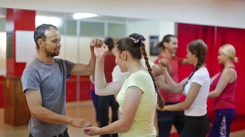  Smiling adults dancing salsa together in dance studio