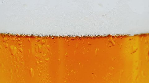close-up of fresh beer with foam into glass as background