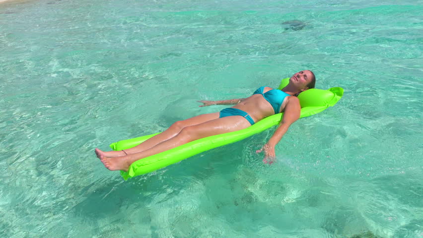 CLOSEUP: Smiling young woman in bikini enjoying and relaxing on inflatable water airbed mattress floating on crystal clear ocean water surface in tropical island | Shutterstock HD Video #14471860