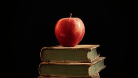 Apple of knowledge. Red apple on book stack.Black background. - Powered by Shutterstock - Get 15% off with code: PIKWIZARD15