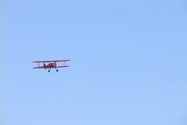 A beautiful, red, vintage airplane fly by.