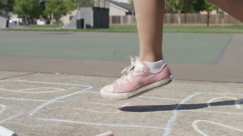 Young girl playing Hopscotch at park, closeup of feet