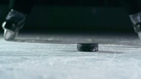 Close-up of hockey puck being struck by hockey player in slow motion