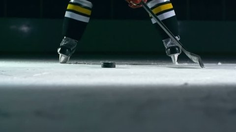 Closeup of hockey player slapping a puck with his stick in slow motion 