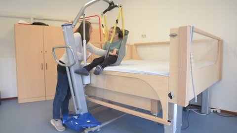 A disabled child being cared for by a special needs carer using specialist equipment / Working together with disability