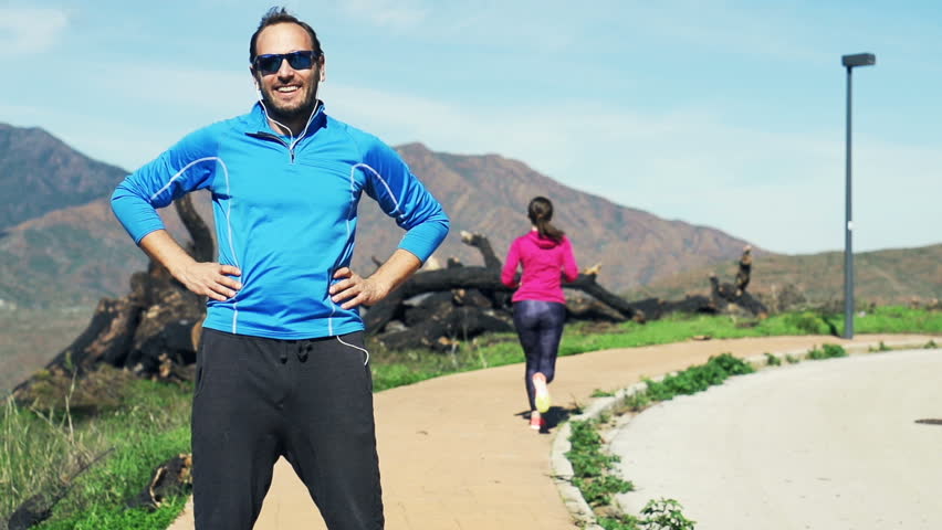Portrait of young happy male jogger in the mountains, super slow motion
