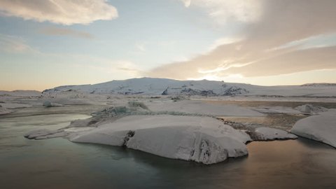 4K Time lapse zoom out of icebergs moving in the Glacier Lagoon Jokulsarlon in Iceland at sunset with dramatic cloud colors