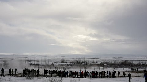 Slowmotion of Geyser Strokkur eruption in Iceland in winter on a cloudy day surrounded by tourists