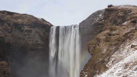 4K Time lapse tilt shot down of Skogafoss waterfall in Iceland in wintertime with a rainbow