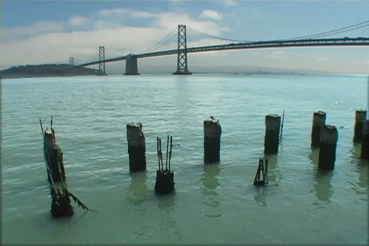 A view of the Bay Bridge with decaying pylons in the foreground.