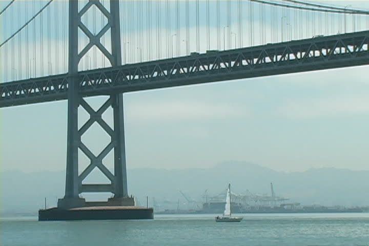 Sailboat passing under the Oakland Bay Bridge.