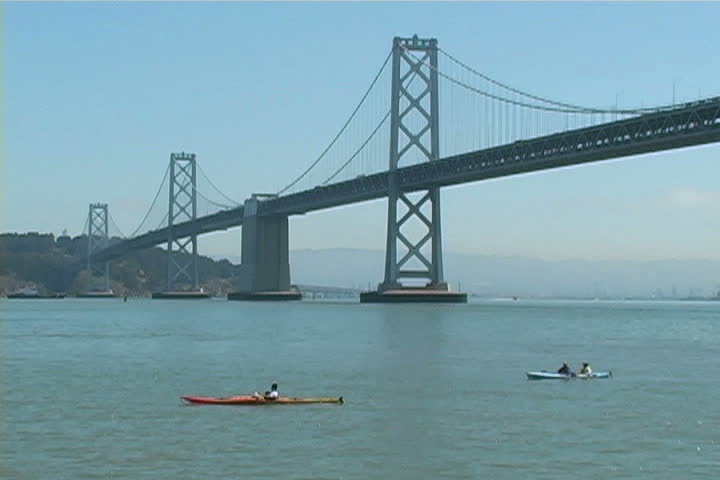 People on kayaks paddling in front of the Bay Bridge. 
