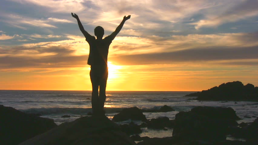 A man with arms outstretched silhouetted against the sunset. Royalty-Free Stock Footage #14517520