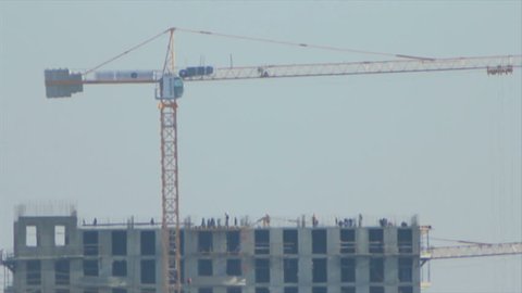 Distant view of silhouettes of people working in the high-rise building construction