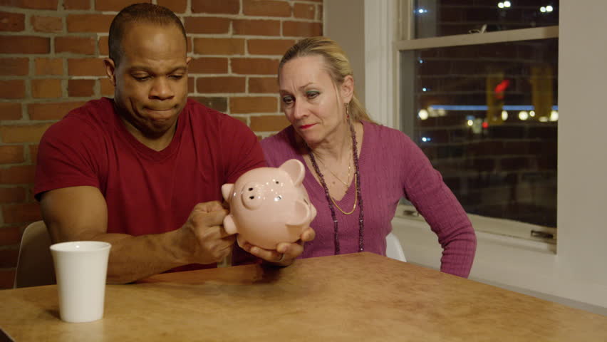 Middle aged interracial couple preparing for retirement with piggy bank