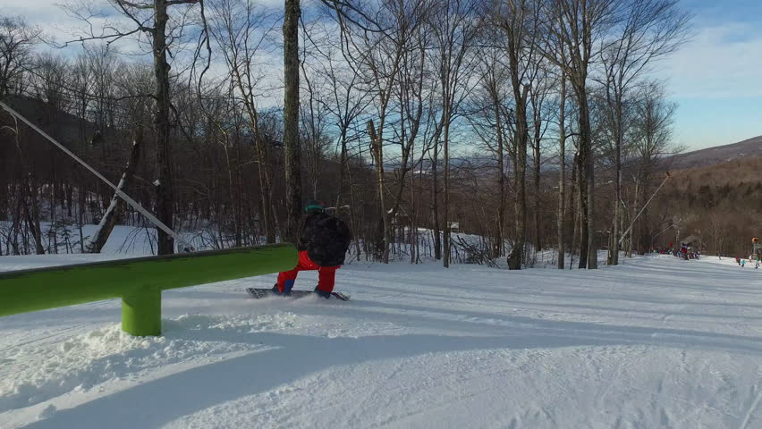 Extreme sport athlete doing grinds on rails and jumps in ski hill snow park